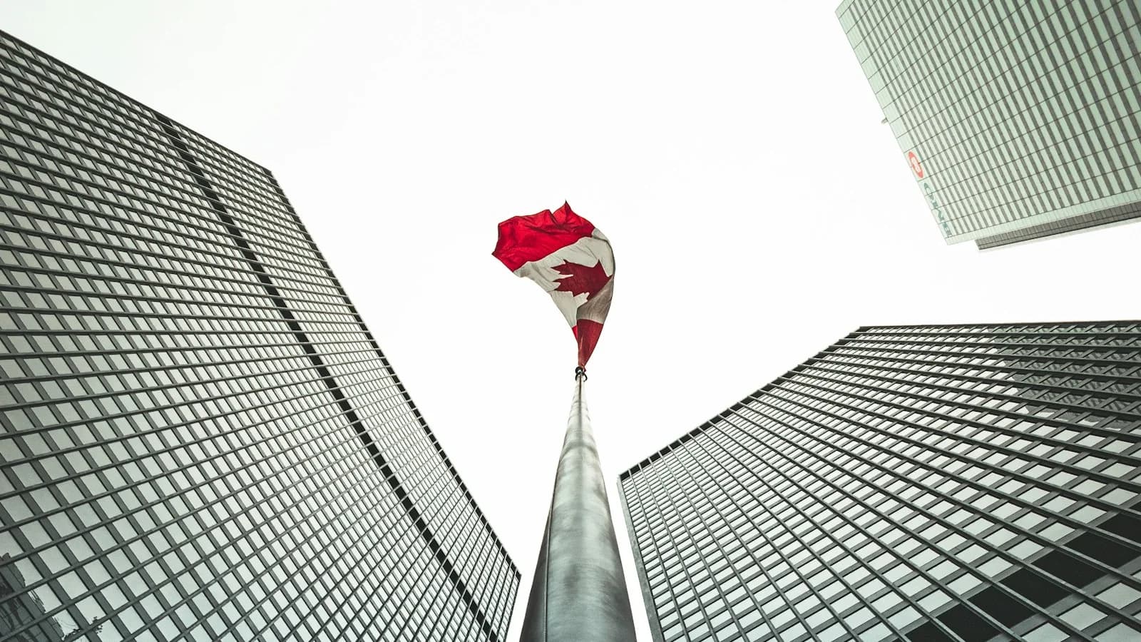 Canadian flag framed by office towers in Toronto’s financial district; contextual photograph.