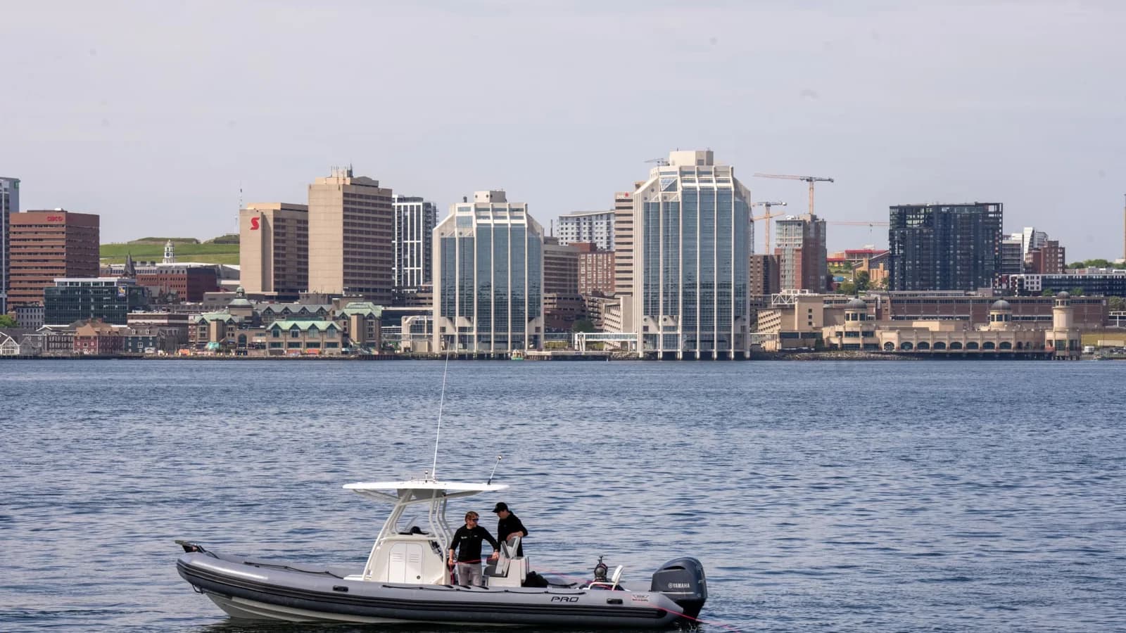 A small workboat conducts a technology demonstration on Halifax Harbour, with downtown Halifax in the background