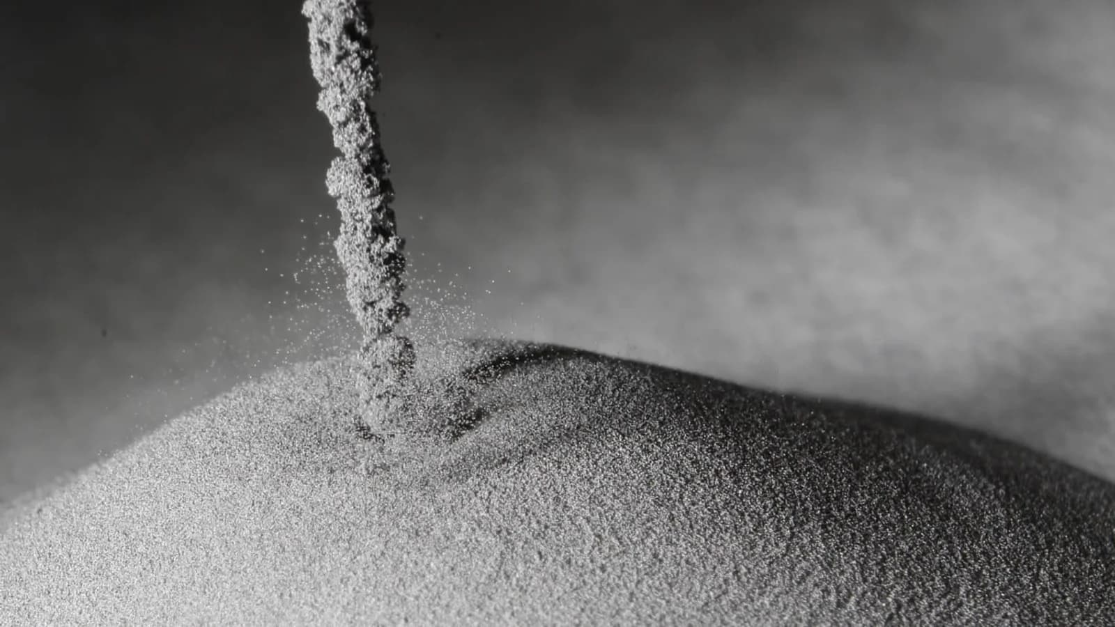 A stream of PyroGenesis titanium metal powder falling onto a mound of powder